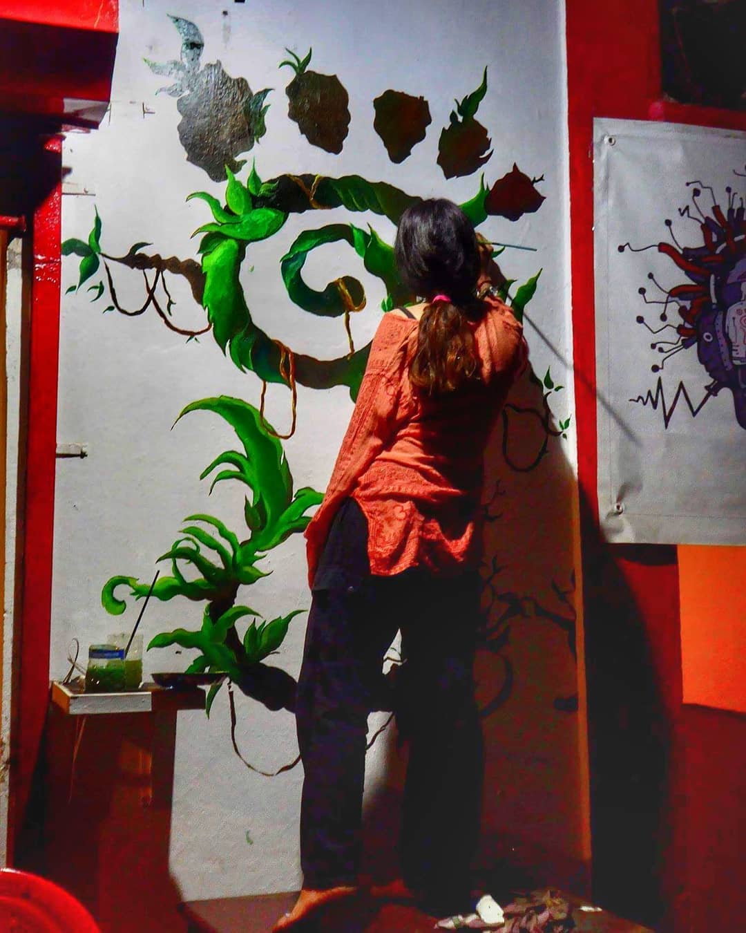 The founder painting a vine mural on a white wall