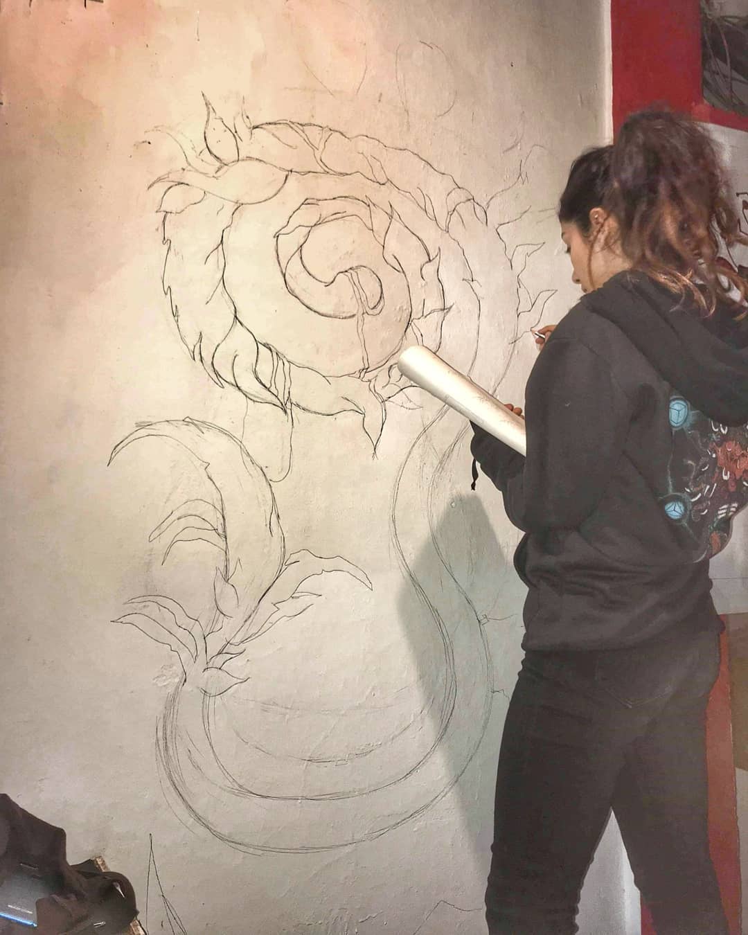 The founder sketching a mural outline on a studio wall